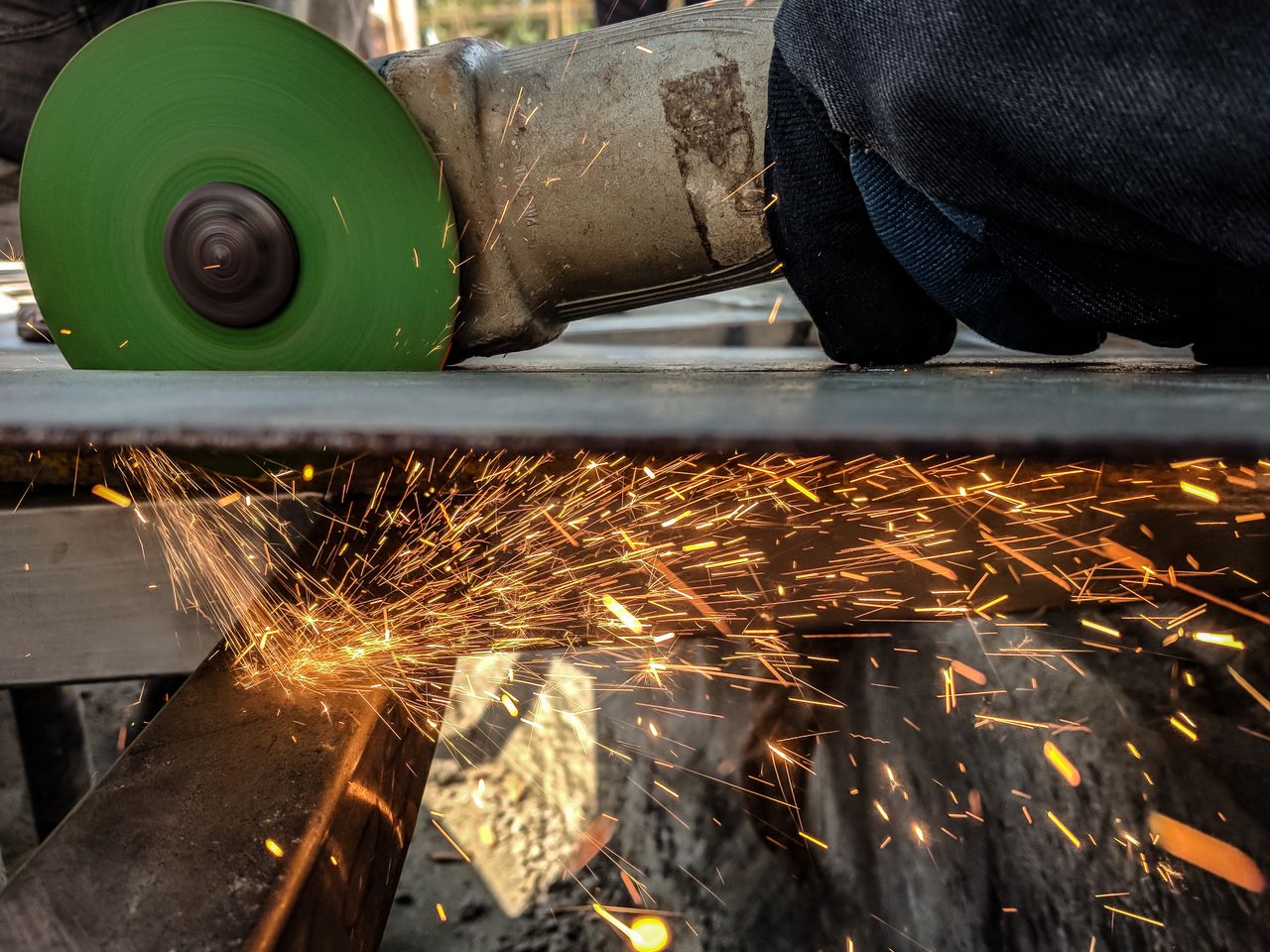 Close-up of a worker using a grinder, creating sparks in a metal workshop environment.
